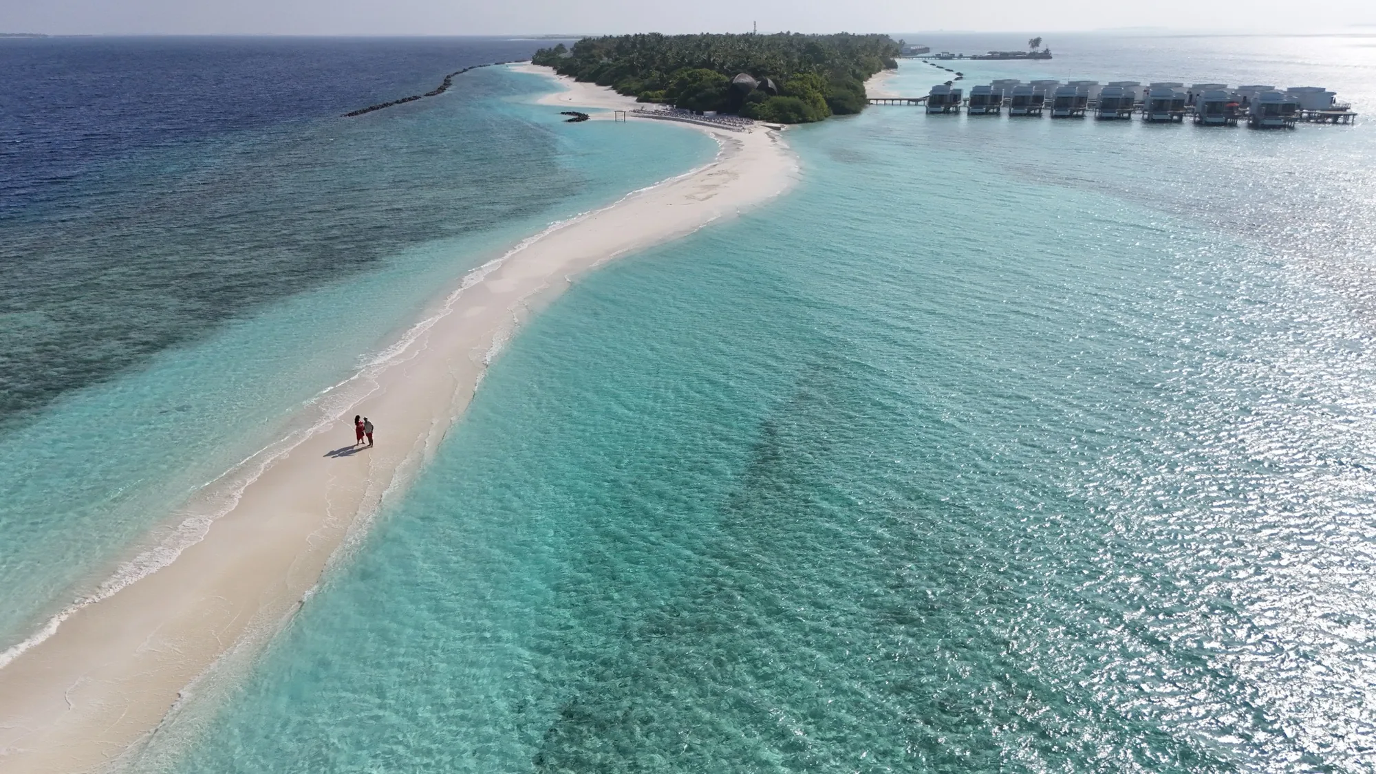 Couple on the beach at Niva Dhigali Maldives with turquoise lagoon and resort
