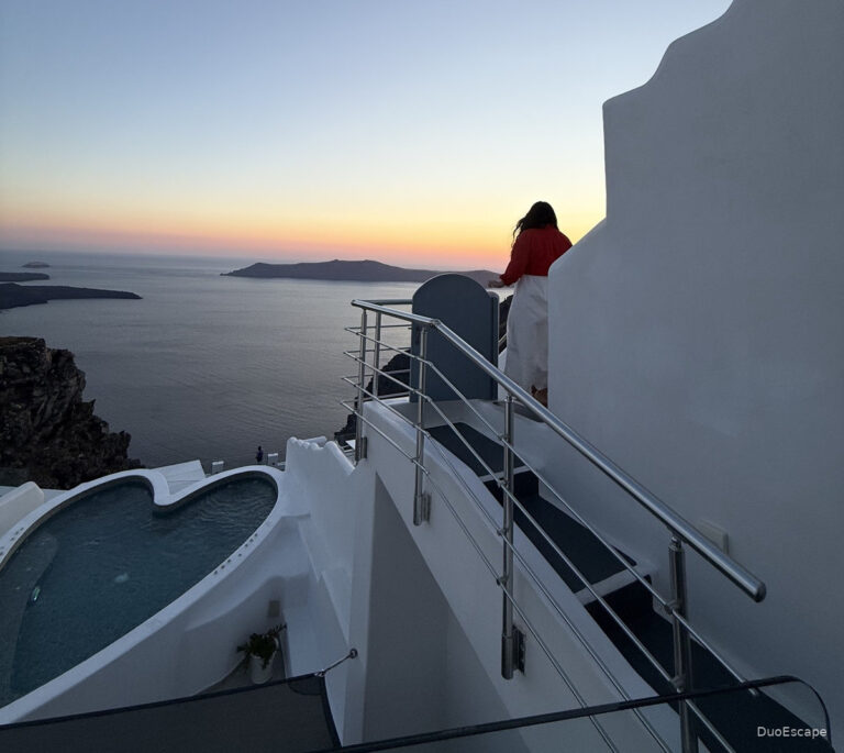 Woman in red overlooking the Santorini caldera at sunset from Pegasus Suites and Spa in Imerovigli