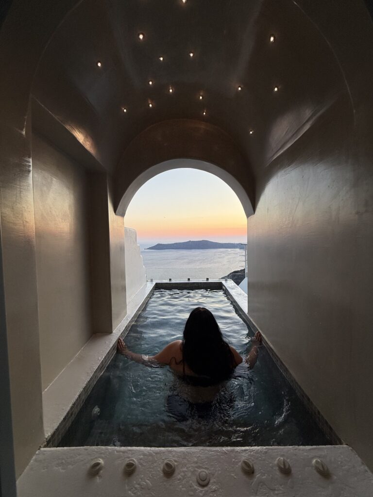 Woman relaxing in private pool at sunset, Pegasus Suites Santorini