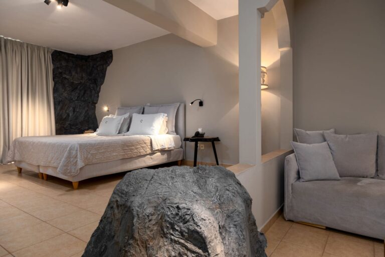 Bedroom and sitting area with exposed rock features in the Cave Suite at Paros Agnanti
