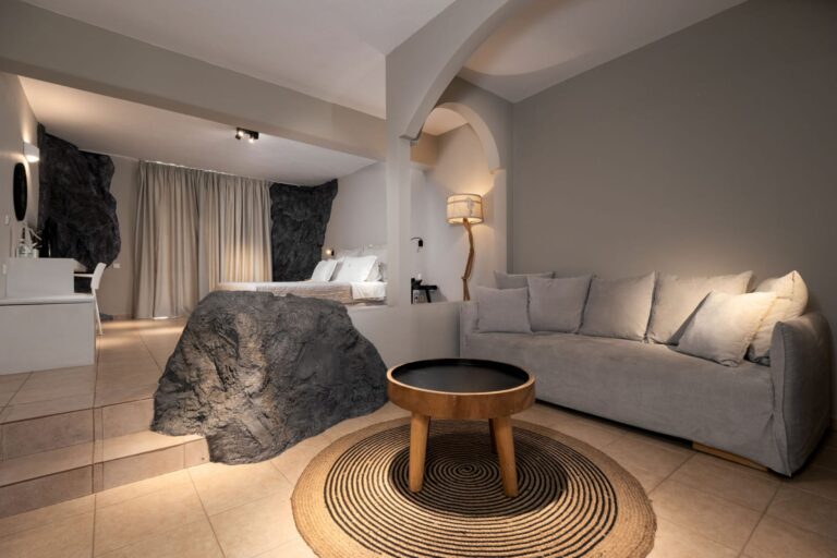 Sofa and sitting area with exposed rock and arches in Paros Agnanti Cave Suite