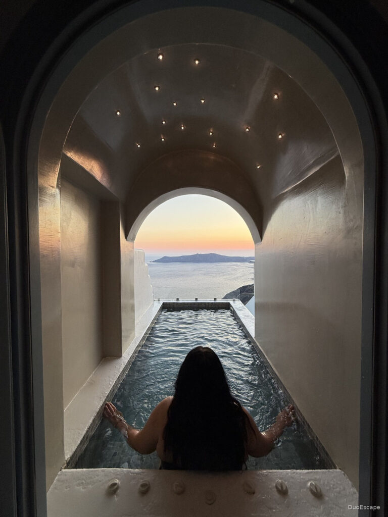 Private pool framed by a curved arch at Pegasus Suites and Spa with Santorini caldera view