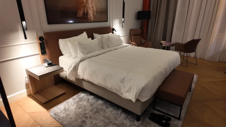 Comfortable white bedding and brown upholstered bench in Radisson Collection Basilica Budapest room