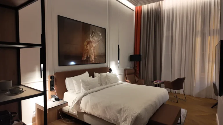 Spacious bedroom with brown armchair and large windows at Radisson Collection Budapest